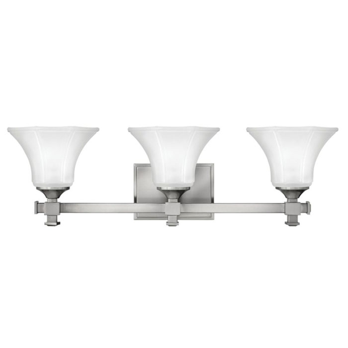 Abbie Collection 3-light vanity fixture with robust square tube construction enhanced by bold decorative cast finials and ribbed, flared six-sided glass shades in brushed nickel finish. Hinkley 5853BN